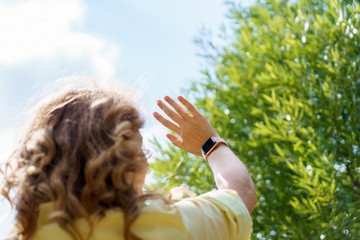 A woman with red hair in yellow shirt lifted hand up standing her back