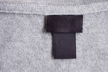Blank black laundry care clothing label on fabric texture