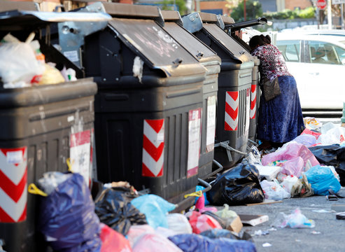 A woman looks into a rubbish bin in Rome