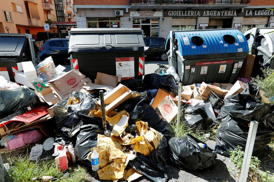 Piles of garbage lie in front of rubbish bins in Rome