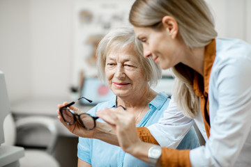 Ophthalmologist offering eyeglasses for vision to a senior woman patient during a medical consultation in the office © rh2010
