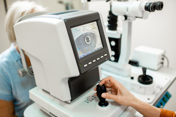Ophthalmologist examining eyes of a senior patient using digital microscope during a medical examination, close-up view