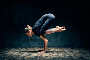 Jonge vrouw die yoga beoefent en onderarmstand doet, pose asana in donkere kamer
