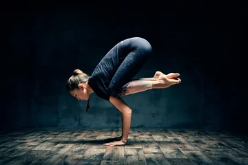 Acrylic prints Yoga school Young woman practicing yoga doing forearm stand crane pose asana in dark room