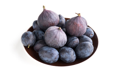 Fruits of blue plum and fig. Isolated ripe fruits on a brown plate on a white background. Side view