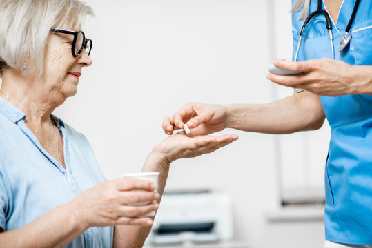 Nurse Giving Some Medicine For A Senior Woman Sitting On The Couch, Taking Care Of Elder Patients In The Hospital