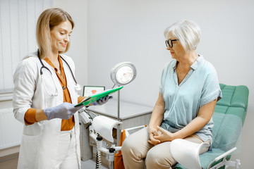 Senior woman sitting on the gynecological chair during a medical consultation with gynecologist....