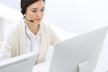 Call center. Beautiful woman receptionist sitting in headset at customer service office. Group of operators at work. Business concept