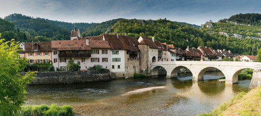 panorama view of a picturesque village with old houses in a river and forest landscape in...