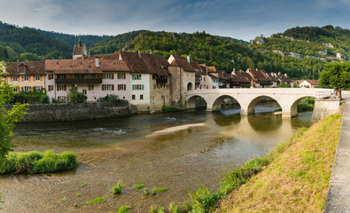 Fototapeta premium panorama view of a picturesque village with old houses in a river and forest landscape in Switzerland
