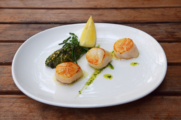 Portion of grilled scallops on plate on table