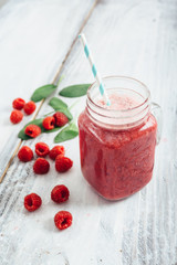 healthy raspberry smoothie in jar on white wooden board with copy space