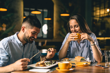 happy young couple eating in restaurant