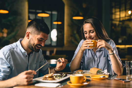 Happy Young Couple Eating In Restaurant