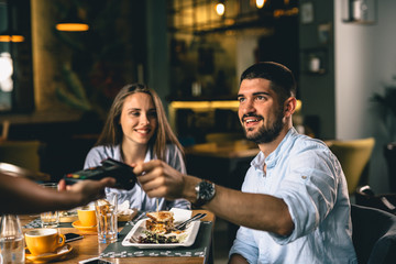 man paying for lunch in restaurant with debit card