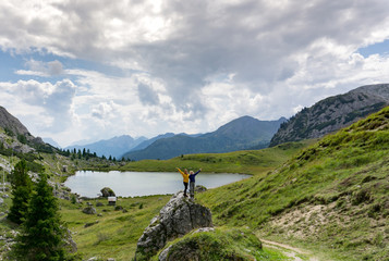 two female hikers stand on a boulder in a pretty mountain landscape in the Dolomites and wave © makasana photo