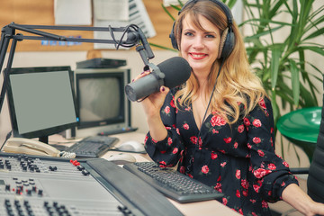 Smiling radio host speaks through a microphone