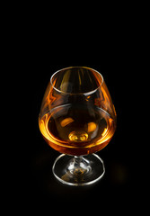 Glass of cognac or brandy isolated on black