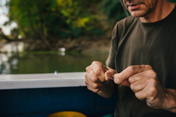 close up of older man preparing equipment for fishing on river