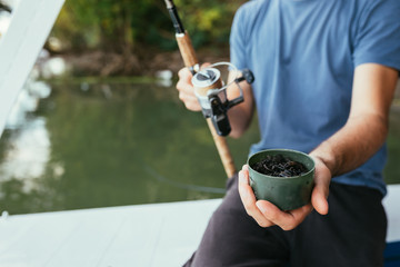 close up of man holding fishing bait earth worms outdoors on river