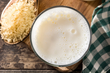 Rice milk in glass and bottle on wooden table. Top view