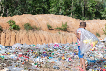 A poor boy collecting garbage waste from a landfill site in the outskirts .  children work at these...