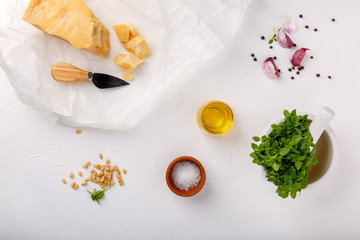 Pesto sauce ingredients - basil, olive oil, pine nuts, parmesan and garlic - on white table. Top...