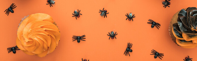 top view of delicious Halloween cupcakes and spiders on orange background with copy space, panoramic shot