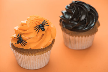 delicious Halloween cupcakes with spiders on orange background