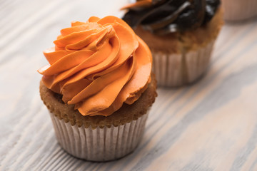 selective focus of delicious Halloween orange cupcake on wooden table