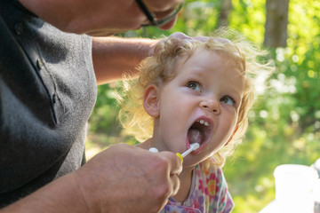 Fototapeta premium Father helps little daughter brush her teeth.
