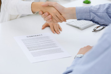 Business people shaking hands at meeting or negotiation after contract discussing. Businessman and woman handshake at office while sitting at the desk. Success concept
