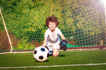 Summer soccer tournament for young kids. football club. emotions and joy of the game. Young goalie. Kids - soccer champion. Boy goalkeeper in football sportswear on stadium with ball. Sport concept.
