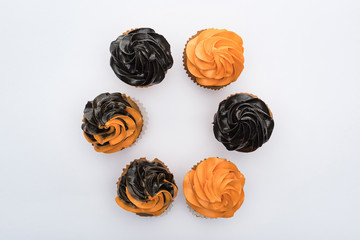 top view of delicious Halloween cupcakes in circle isolated on white