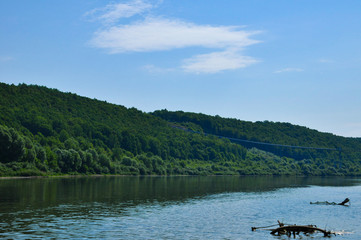 Riverscape on a summer day with Oka river, forest growing on a river bank and cloudy sky