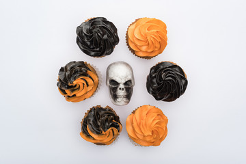 top view of delicious Halloween cupcakes around skull isolated on white