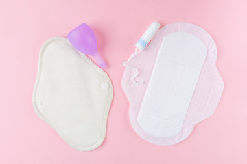 Reusable eco-friendly female pad, menstrual cup, tampon and usual women's pad. Pink background, place for text, minimalism, top view, flat lay. Zero waste concept..