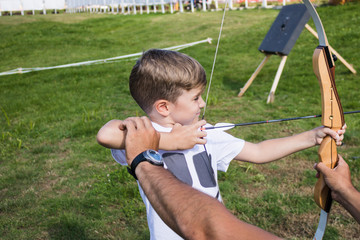 Little boy learning to aim with bow and arrow.