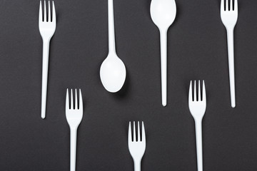 Plastic forks and spoons on gray background