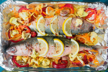  Fish with vegetables and lemon, tomatoes and spices prepared for baking in a bacon. Top view. Close-up.