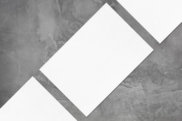 Closeup of three empty white rectangle poster or card mockups lying diagonally with soft shadow on...