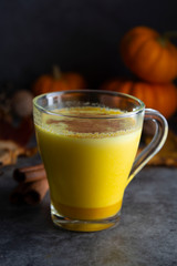 Pumpkin spiced latte macchiato on a dark wooden background autumn drink beverage golden milk