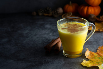 Pumpkin spiced latte macchiato on a dark wooden background autumn drink beverage golden milk with copy space