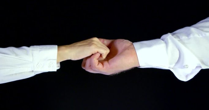 Close - up of a woman and a man's hand in white sleeves on a black background interlock and disengage.