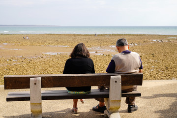 Senior retired couple looking sea sit on bench at Saint Vincent sur Jard in vendée beach France