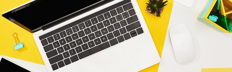 top view of laptop with blank screen and computer mouse on yellow and white background