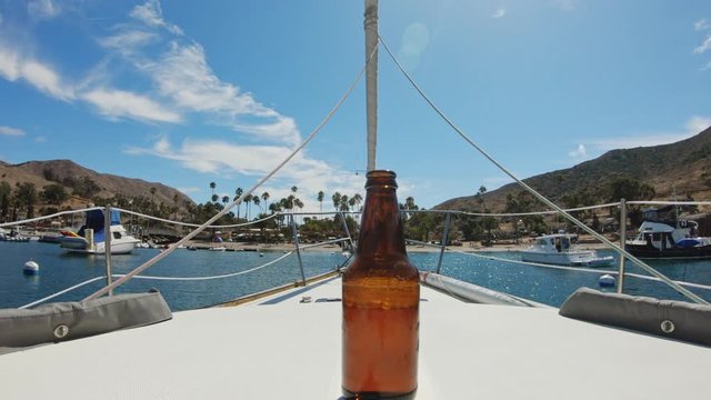 Glass Bottle Centered On Sailboat Bow With Catalina Island In The Background.