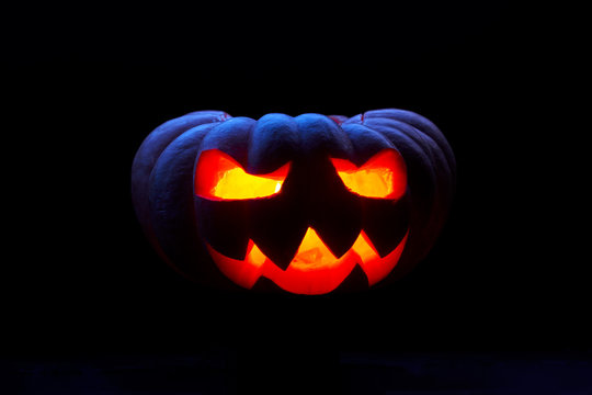 Close up image of one halloween pumpkin with burning mouths on empty black background