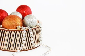 shiny multi-colored Christmas balls toys in a decorative wooden basket for the New Year holiday