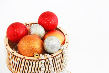 shiny multi-colored Christmas balls toys in a decorative wooden basket for the New Year holiday